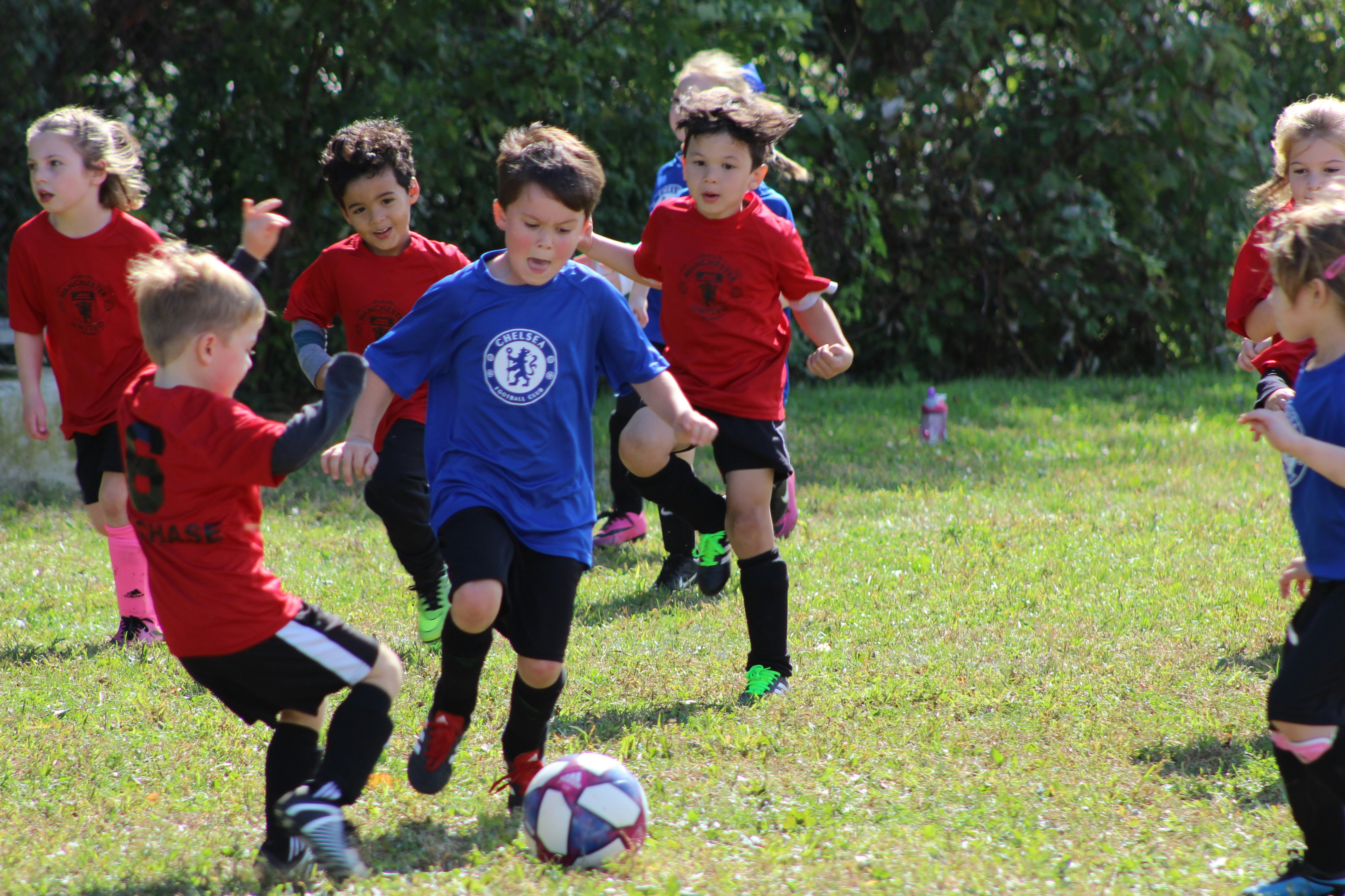 young children playing soccer outside